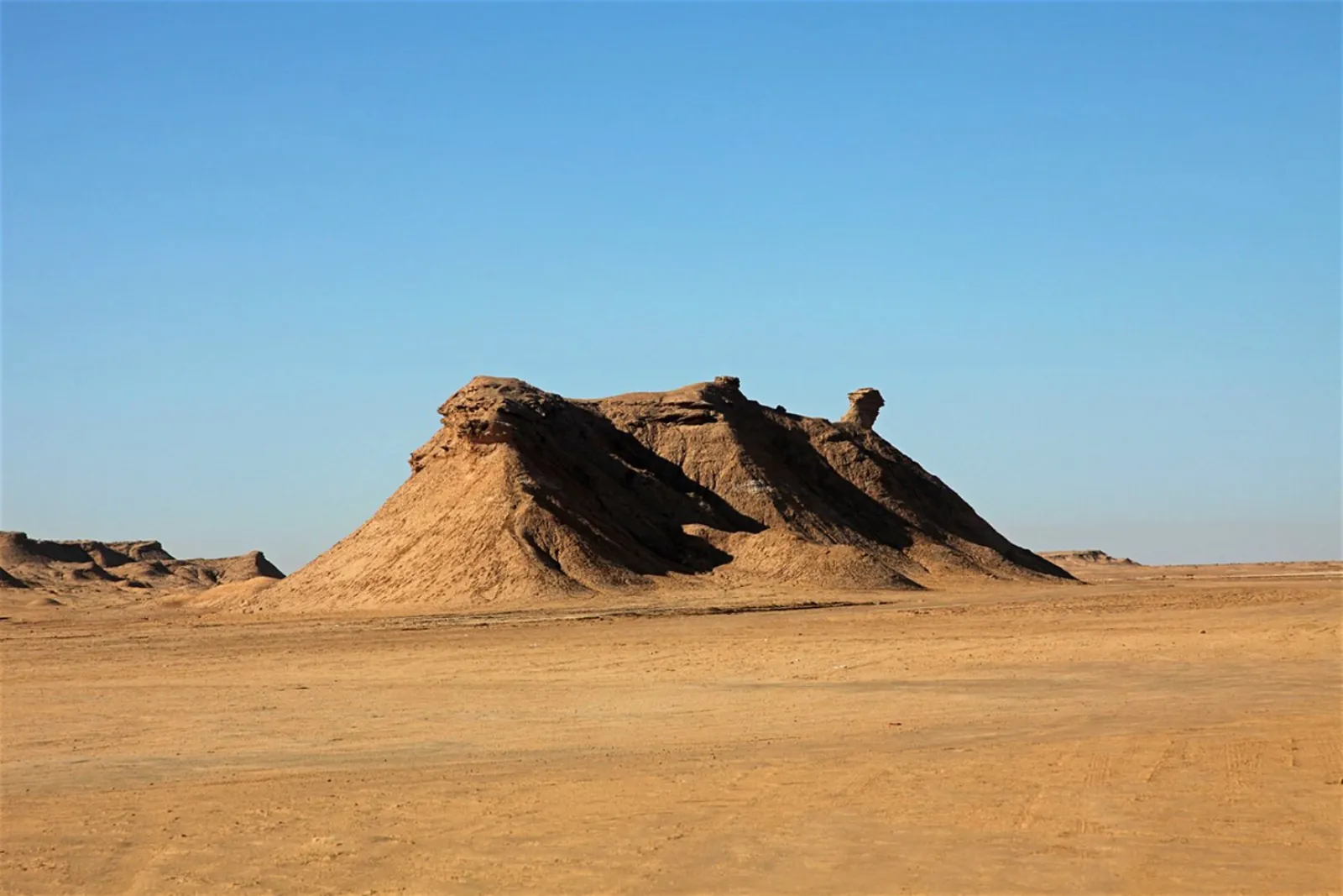 The Ong Jmal rock formation rising from the flat desert like a kneeling camel