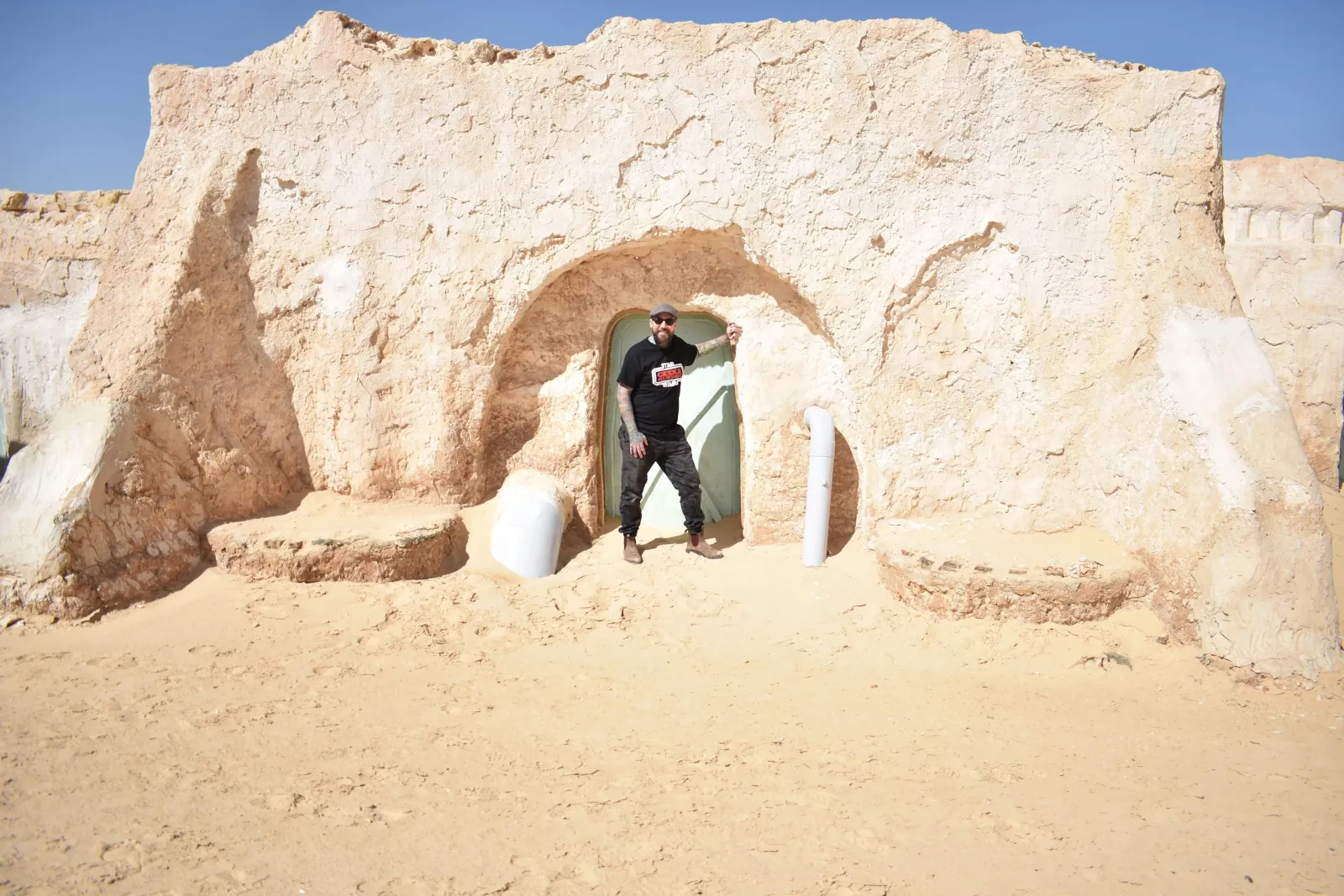 A visitor standing in the arched doorway of a Mos Espa building