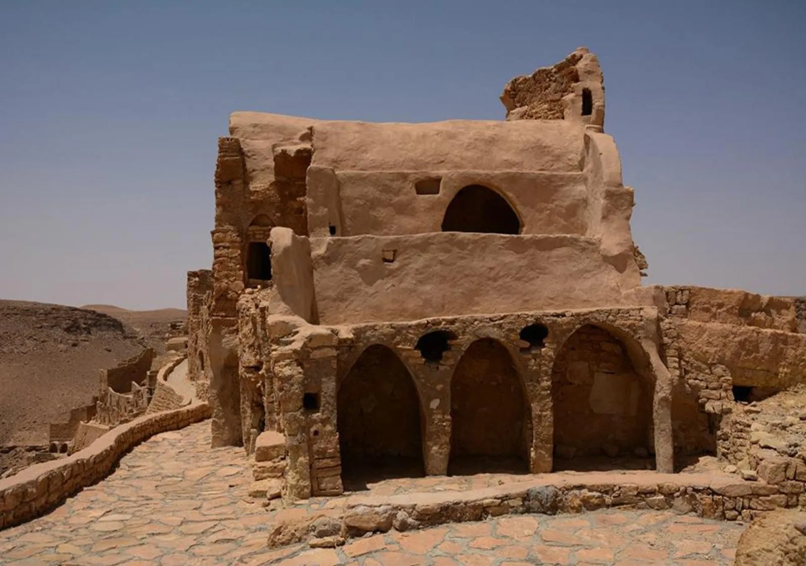 A stone ksar building with arcaded storage cells standing on a bare ridge