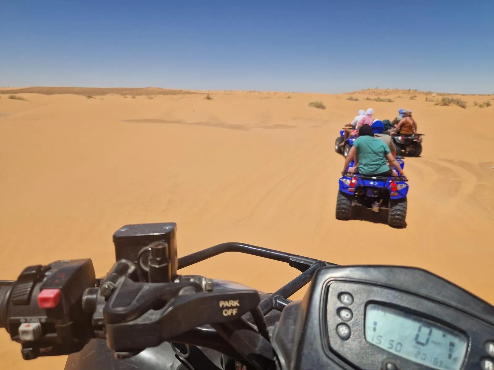 Rider's view from a quad bike following others across the dunes at Ksar Ghilane