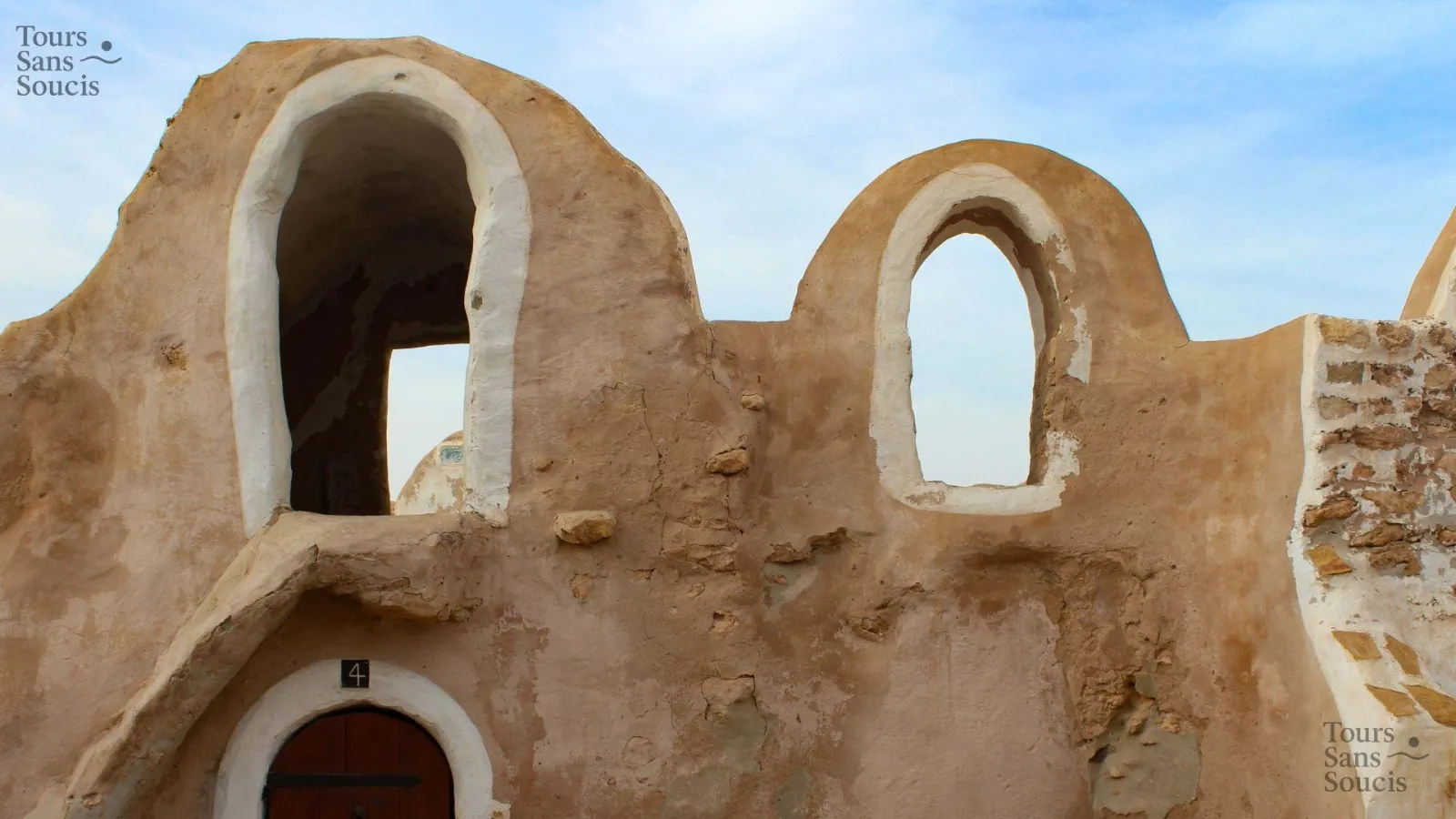 Two whitewashed arched openings in the mud-rendered upper wall of a ksar
