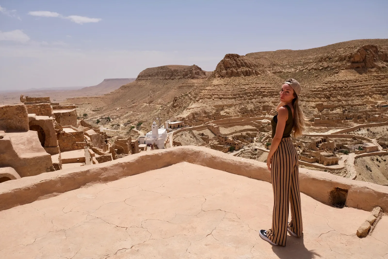 A visitor on a flat roof above Chenini, looking out over the white mosque and the valley